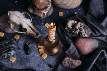 Old dog skull, burning candle, wooden runes and stones on the witch table.の写真素材