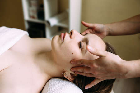 Masseur doing massage on a womans face at the spa.の写真素材