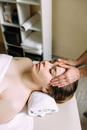 Masseur doing massage on a womans face at the spa.の写真素材