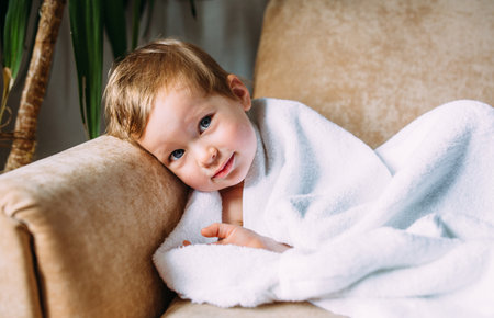 Cute child with blue eyes wrapped in a white towel.