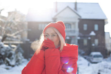 Young stylish blonde woman on the street has fun, posing in snowy, frostyの写真素材