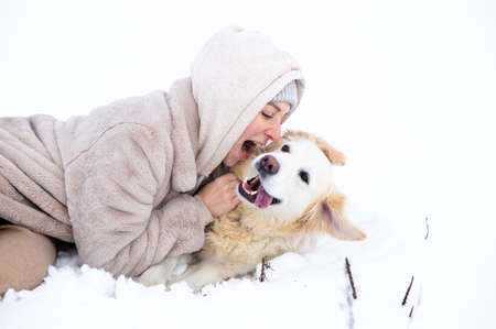 Young beautiful woman and her golden retriever dog having fun in winter.の写真素材
