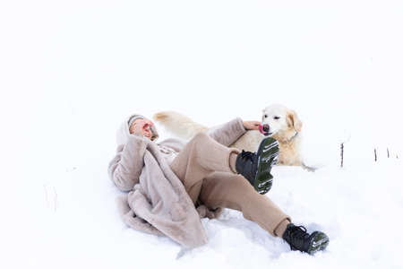 Young beautiful woman and her golden retriever dog having fun in winter.