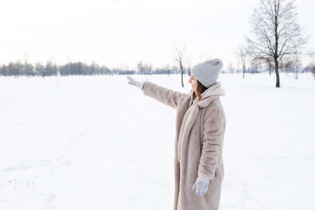 Young girl in beige clothes, fur coat made of artificial fur walks in winterの写真素材