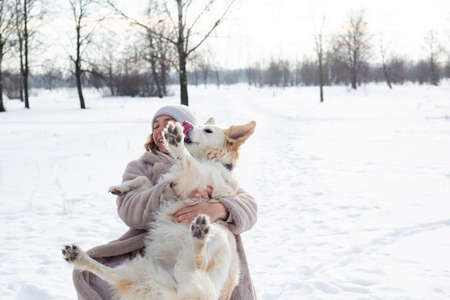 Young beautiful woman and her golden retriever dog having fun in winter.の写真素材