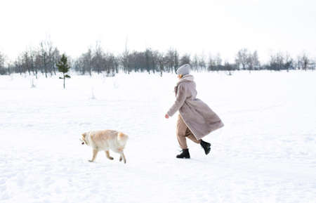 Young beautiful woman and her golden retriever dog having fun in winter.の写真素材