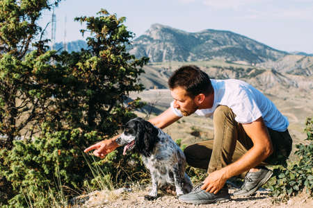 Male owner of spaniel dog walking against mountains background.の写真素材