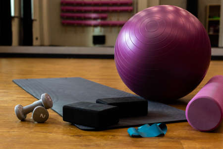 Set of sports equipment with fitness ball and yoga mat in the gym on the floor