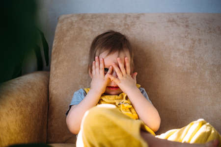 Funny little child is having fun, playing with soft toys on the couch at home.