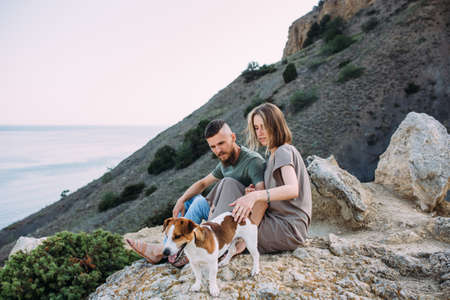 Happy couple with favourite pet. Young man and woman have walk near sea.の写真素材