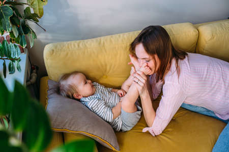 Mom plays at home with a small child on the couch, have fun.