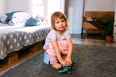 Cute toddler girl, potty training, playing with his toys on pottyの写真素材