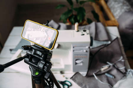 Shooting video of the sewing process, workshop on clothing design on smartphoneの写真素材