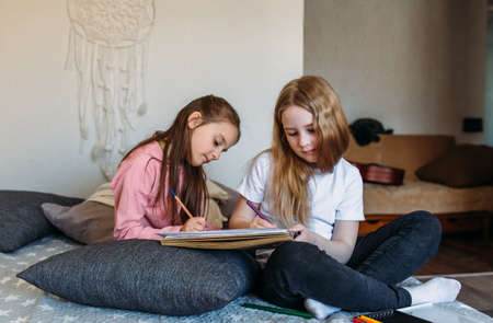Two girls friends play at home, draw with pencils and felt-tip pens and have funの写真素材