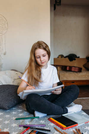 The girl after school plays at home, draws with pencils and felt-tip pensの写真素材