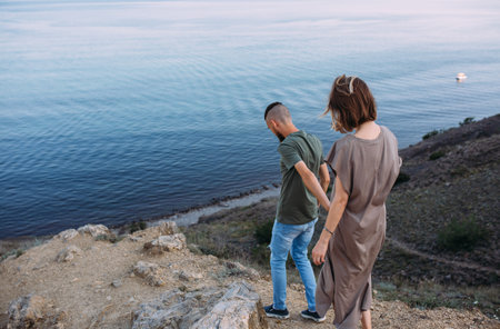 Stylish lovely couple walking and hugging by the sea enjoying time togetherの写真素材