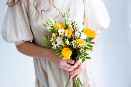 Beautiful woman with spring yellow bouquet of flowers spring and beauty conceptの写真素材