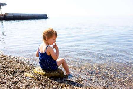 Little cute child girl playing on the seashore in summerの写真素材
