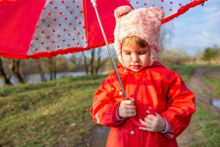 Child plays with umbrella after the rain in red rubber boots and a raincoat.の写真素材