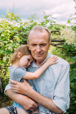 A little girl hugs her grandfather on a walk in the summer outdoors.の写真素材