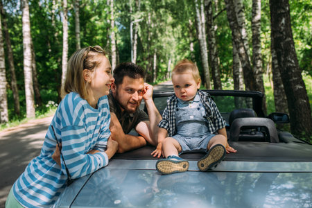 Mom, dad and little son in a convertible car. Summer family road trip to natureの写真素材