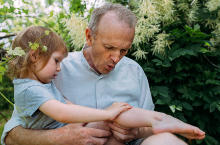 A little girl hugs her grandfather on a walk in the summer outdoors.の写真素材