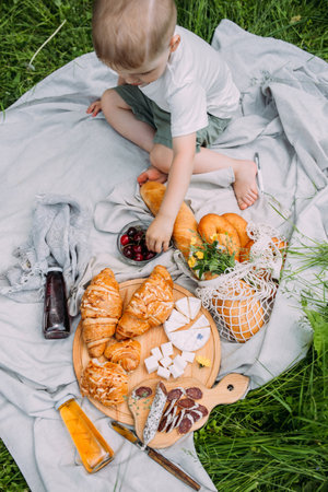 Boy child preschooler on a picnic. Smiles, eating cherries and enjoying summer.の写真素材