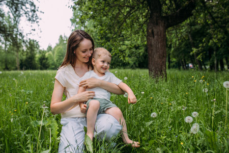 Young woman mom and son play in nature, spend time together and have funの写真素材