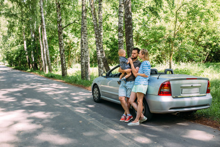 Mom, dad and little son in a convertible car. Summer family road trip to natureの写真素材