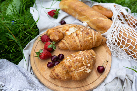 Picnic in the field with berries, juice, cheese, sausage and sweet croissantsの写真素材