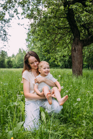 Young woman mom and son play in nature, spend time together and have funの写真素材