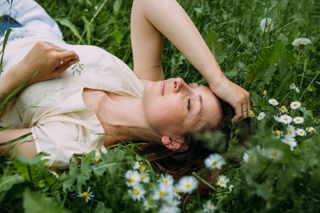 Beautiful woman with natural beauty without makeup lies in the grass in summerの写真素材