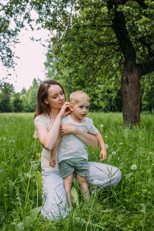 Young woman mom and son play in nature, spend time together and have funの写真素材