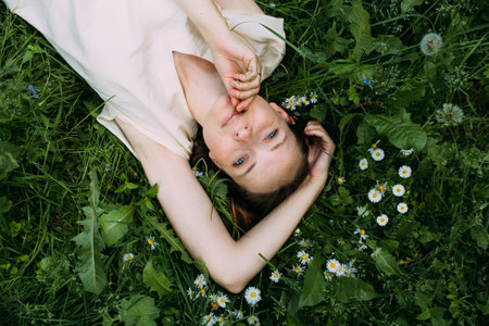 Beautiful woman with natural beauty without makeup lies in the grass in summerの写真素材