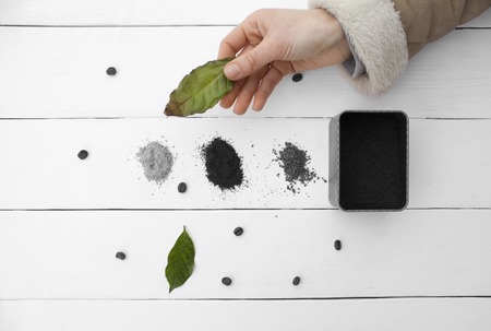 Creative work sheet coffee in his hand a female hand. Green leaves drying soil, types of coffee on a wooden table top white, black and white coffee beansの写真素材
