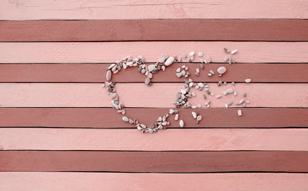 Heart laid out from the stone crumbles on a wooden surface pale red stripes.の写真素材