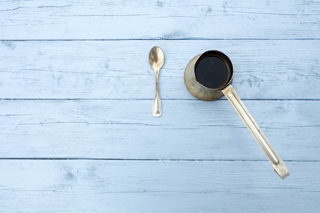 Metal coffee Turk and spoon on a rough wooden surface light blue