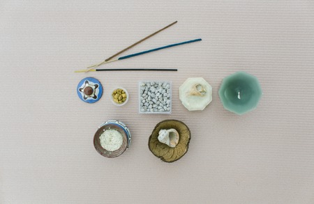 The composition of the components of a meditation on light beige background. Church and Indian incense and incense, candles and shells, a pot of rice as a stand rod.の写真素材