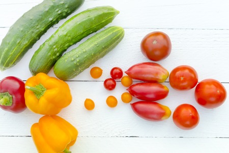 Organic food background. Cucumber, bell pepper, tomatoes, tomatoes of cherri. Food photography different vegetables, white backgroundの写真素材