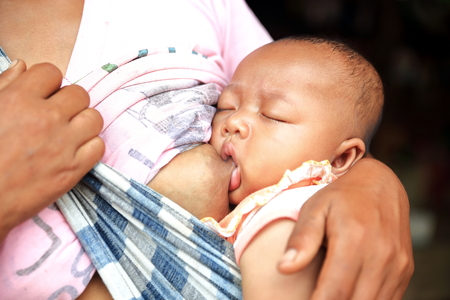 LUANG NAMTHA,LAOS-OCTOBER 06, 2015: Mother breastfeeding her baby in front of strangers without shame on October 06, Luang Namtha, Laos.のeditorial素材