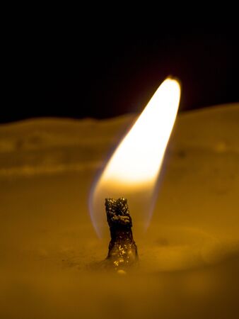 the swaying tongue of a candle flame on a black background close-upの写真素材