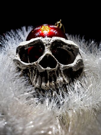 holiday card with menacing white human skull with the christmas ball and christmas decoration  on a black background close-up. front viewの写真素材