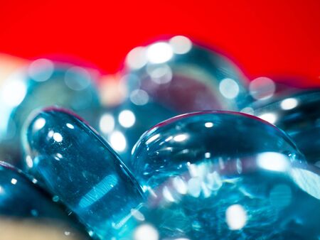 close-up of blue translucent glass stones with white highlights on a red backgroundの写真素材