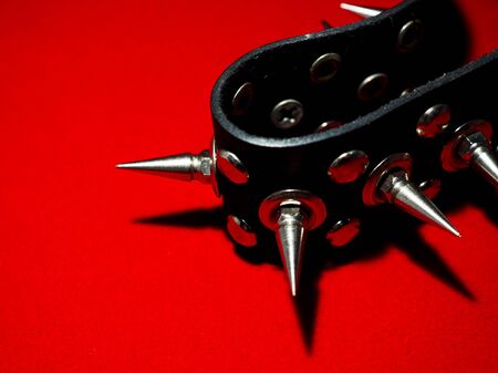 black bdsm collar with metal spikes on a red background with sharp shadowsの写真素材