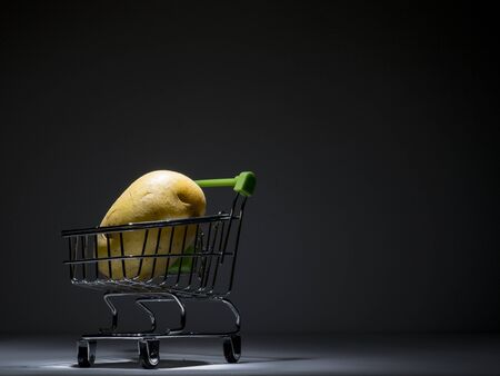 fresh young potato in a tiny supermarket trolley on black background, still life, packshotの写真素材