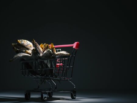 fresh sprat in a tiny supermarket trolley on black background, still life, packshotの写真素材