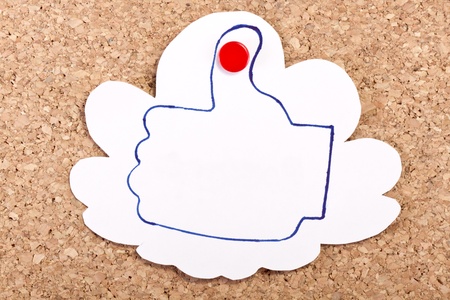 Cloud shape paper note with a like thumb drawing inside with a pen on a corkboard.