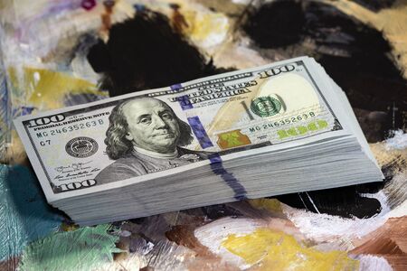 Money on a colored wooden background. Stack of one hundred dollars bills on wooden desk. New design.