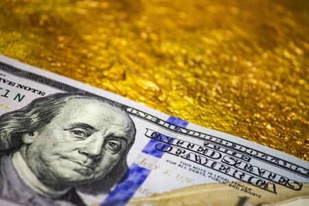 Close-up of One hundred dollar banknote on a gold close-up. Dollar versus gold concept.の写真素材