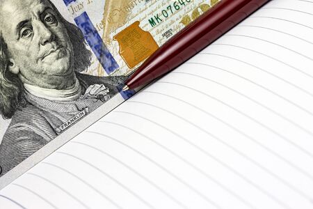 Close up of business notepad and a pen with one hundred US dollars and empty space for textの写真素材